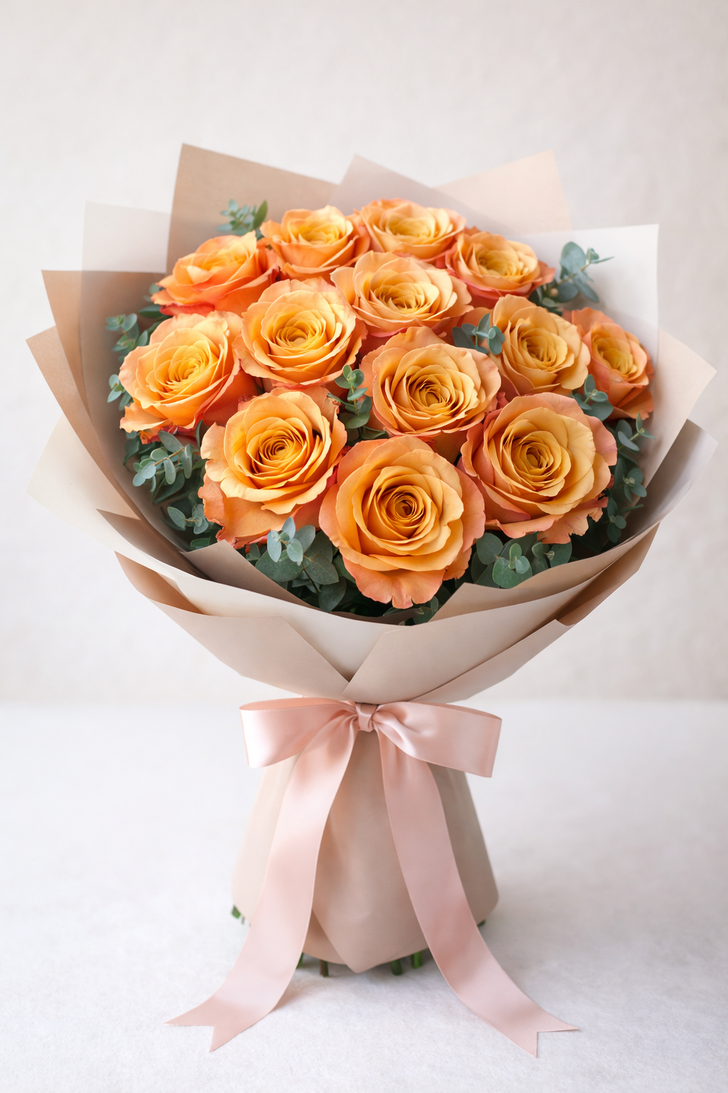 Bouquet of orange roses wrapped in brown paper with a pink ribbon on a light background