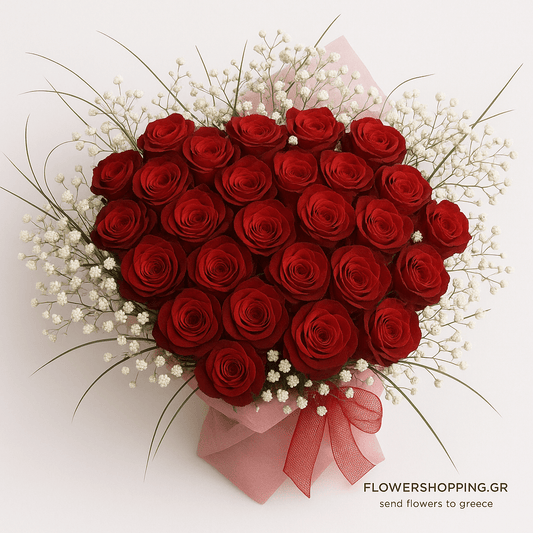 Heart-shaped bouquet of realistic deep red roses surrounded by white baby's breath and green foliage, wrapped in pink paper with a red ribbon, placed on a soft white background. Discreet text at the bottom reads "flowershopping.gr – send flowers to greece